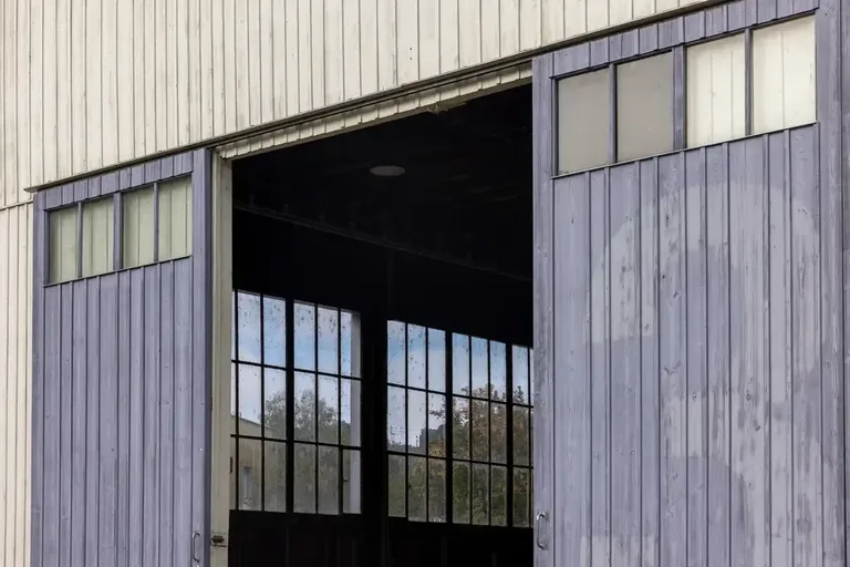 Geöffnete industrielle Schiebetore im Vitus-Areal Winterthur mit Blick auf die grossen, historischen Fenster der Halle.