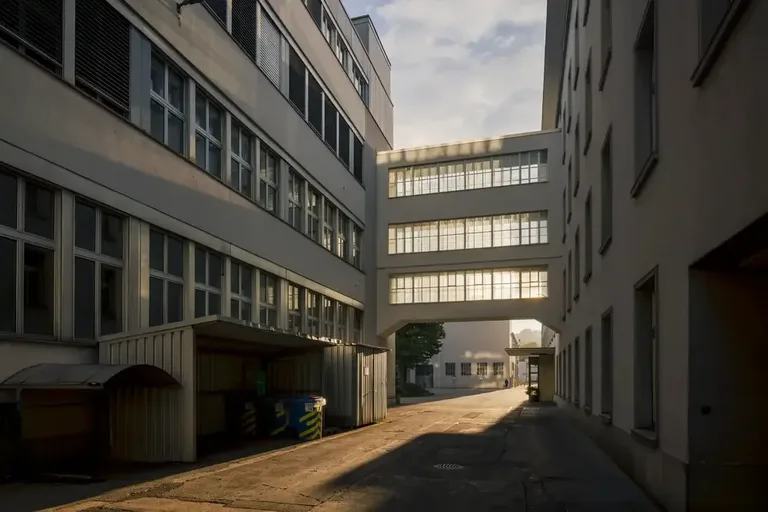Industriegebäude im Vitus-Areal Winterthur mit verglastem Verbindungsgang und Abendlicht im Innenhof.